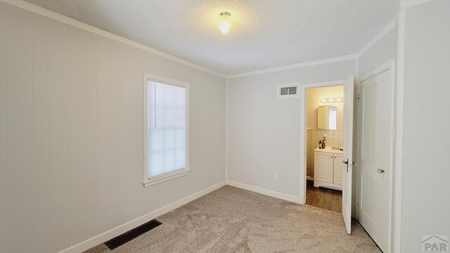 unfurnished bedroom with visible vents, ornamental molding, a textured ceiling, and light colored carpet