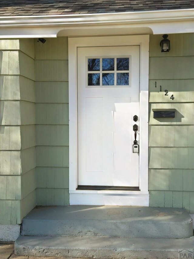 doorway to property featuring roof with shingles