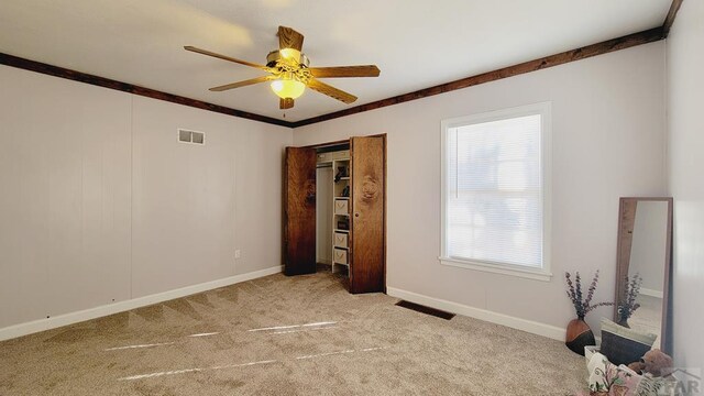 unfurnished bedroom featuring light carpet, baseboards, visible vents, and crown molding