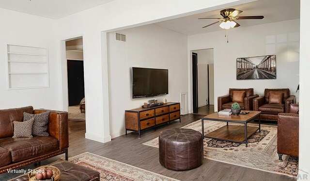 living area featuring dark wood-style floors, ceiling fan, built in shelves, and visible vents