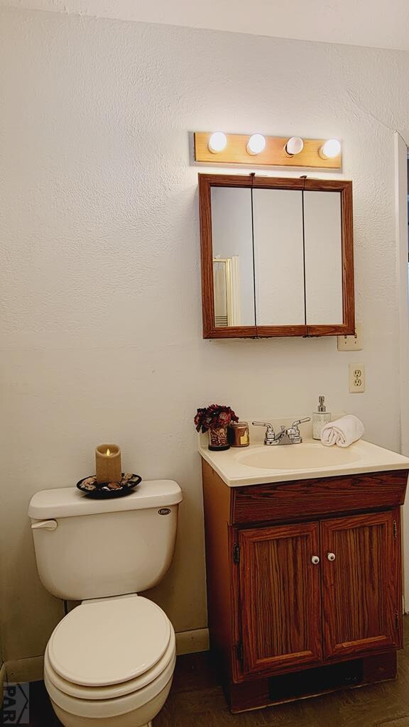 half bathroom featuring vanity and toilet