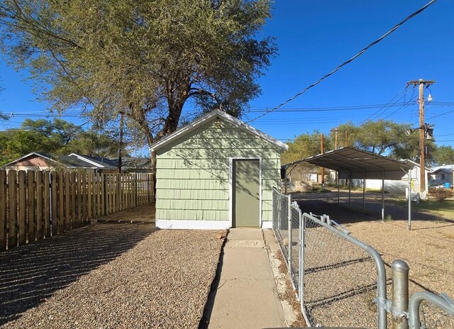 view of shed featuring a carport and fence