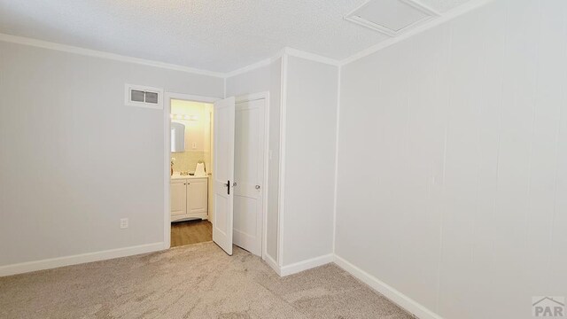 unfurnished room featuring attic access, visible vents, baseboards, light colored carpet, and ornamental molding