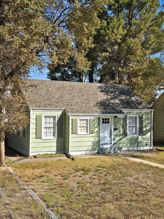 view of front facade featuring a shingled roof and a front lawn