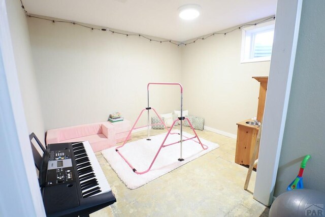 rec room with baseboards and unfinished concrete floors