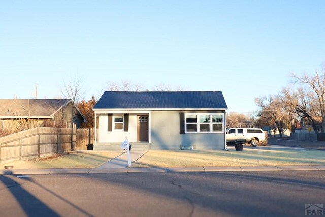 view of front of home with metal roof, fence, and stucco siding