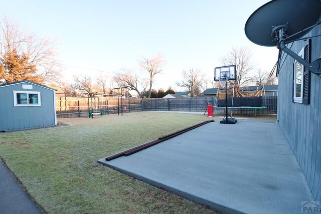 view of sport court featuring a fenced backyard, playground community, a lawn, a shed, and a trampoline