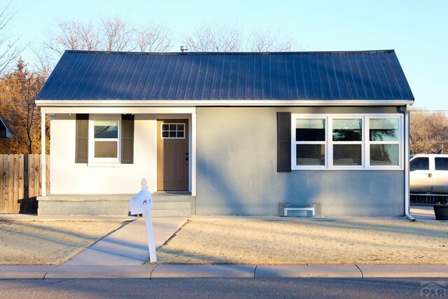 view of front facade with heating fuel, fence, and metal roof