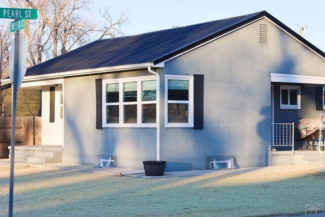 view of side of home with entry steps, metal roof, and stucco siding