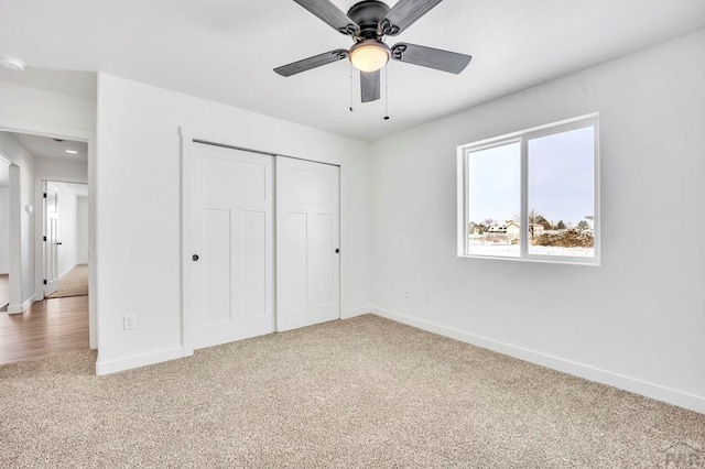 unfurnished bedroom featuring carpet floors, a ceiling fan, baseboards, and a closet