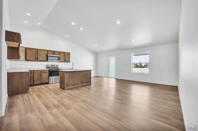 kitchen with stainless steel appliances, open floor plan, light countertops, and light wood-style floors