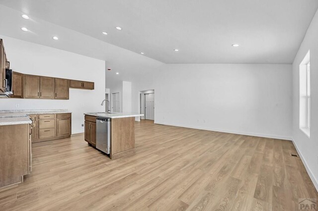 kitchen featuring an island with sink, light countertops, dishwasher, and open floor plan