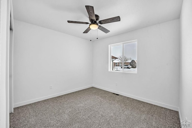 carpeted empty room with visible vents, baseboards, and a ceiling fan