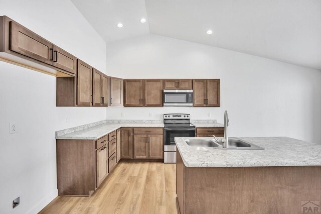 kitchen featuring stainless steel appliances, a sink, light countertops, light wood-type flooring, and brown cabinets