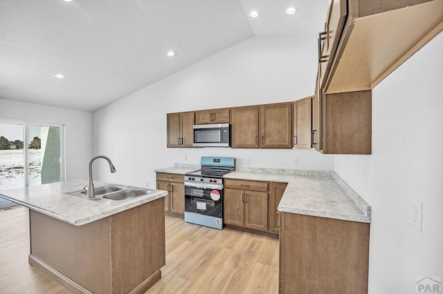 kitchen featuring stainless steel appliances, brown cabinets, a sink, and a center island with sink