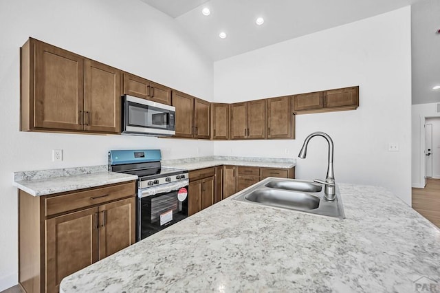 kitchen featuring high vaulted ceiling, appliances with stainless steel finishes, a sink, and recessed lighting