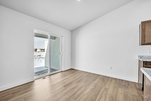 unfurnished room with light wood finished floors, visible vents, and baseboards