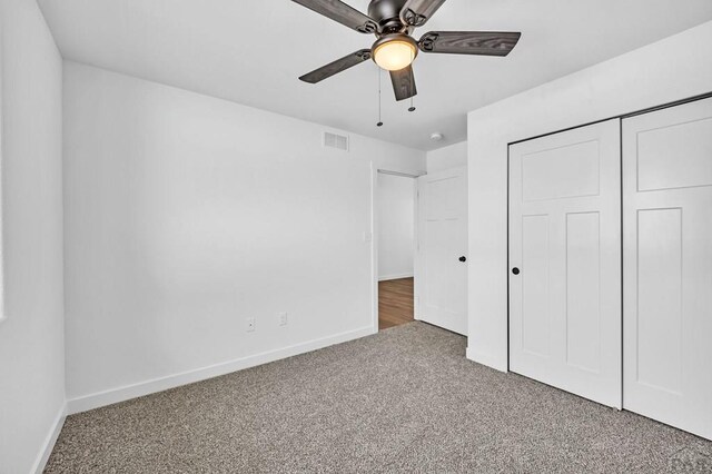 unfurnished bedroom with a closet, visible vents, a ceiling fan, carpet flooring, and baseboards