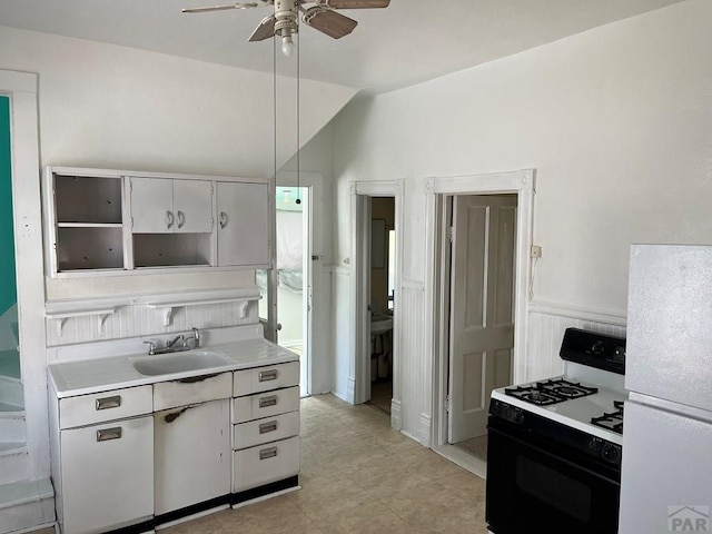 1410 E Orman Ave, Pueblo, CO 81004 - kitchen featuring gas stove, freestanding refrigerator, ceiling fan, light countertops, and white cabinets