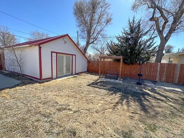 view of yard with fence, an outdoor structure, and french doors