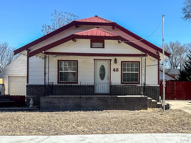 view of front of house with a garage, fence, a porch, and brick siding