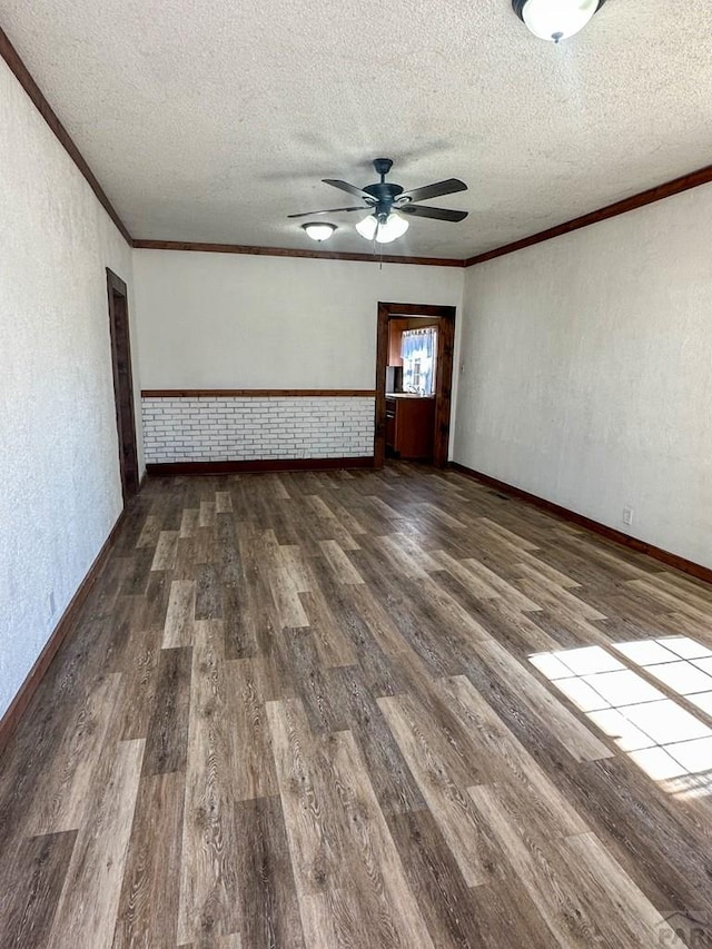 empty room with a textured ceiling, wood finished floors, and crown molding