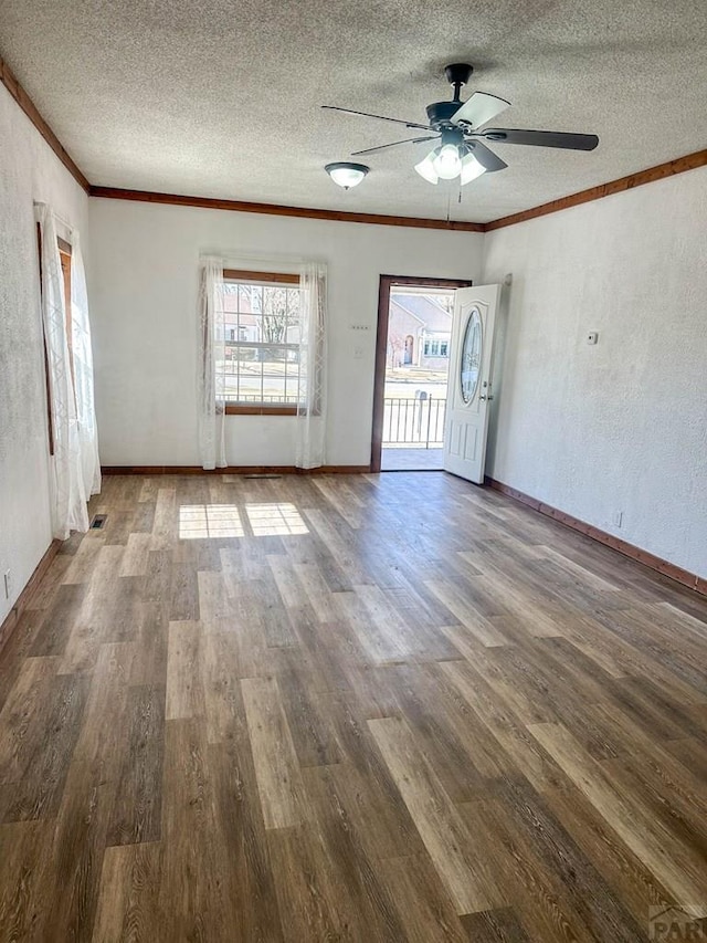 unfurnished living room featuring baseboards, ceiling fan, wood finished floors, crown molding, and a textured ceiling