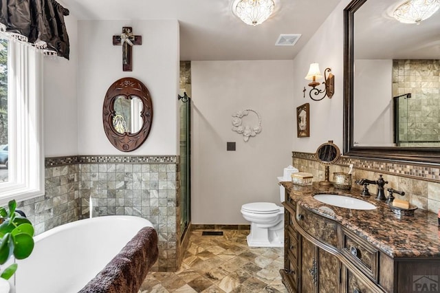 bathroom with visible vents, a shower stall, toilet, a soaking tub, and vanity