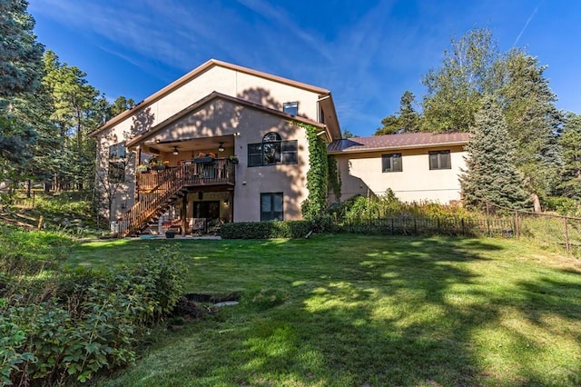 back of house featuring stucco siding, a ceiling fan, fence, stairway, and a yard