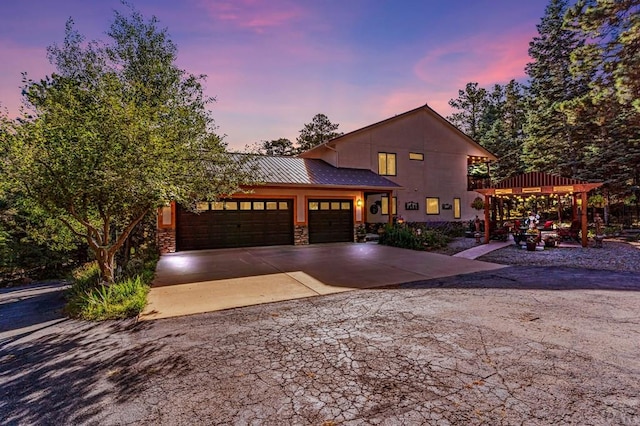 view of front facade featuring metal roof, a garage, stone siding, driveway, and a standing seam roof