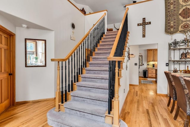 stairs featuring baseboards, a high ceiling, and wood finished floors