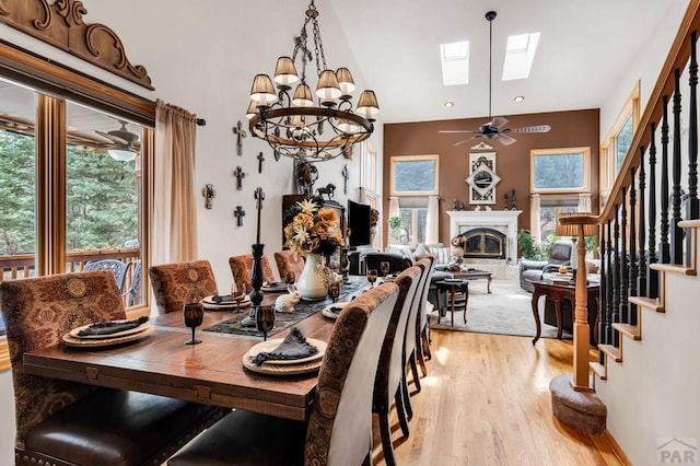 dining room with light wood finished floors, a glass covered fireplace, stairway, and a wealth of natural light