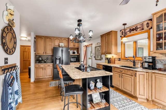 kitchen featuring light wood finished floors, open shelves, a sink, black appliances, and a center island