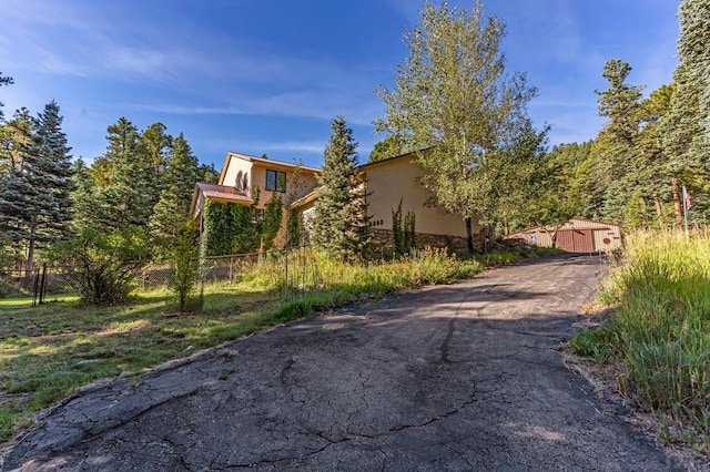 view of property exterior with stucco siding, driveway, and fence