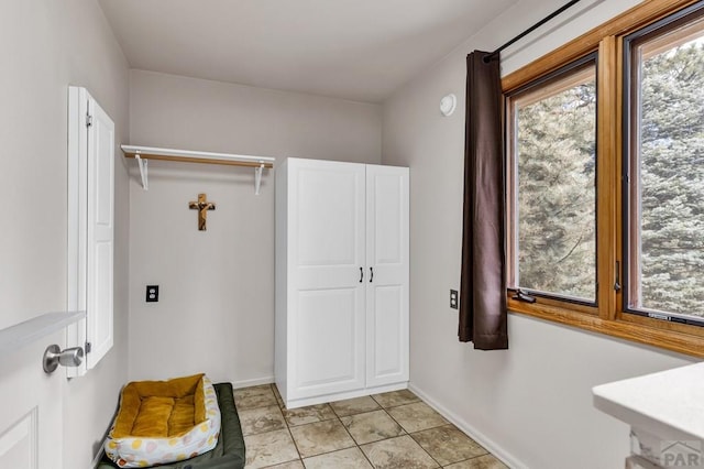 interior space featuring light tile patterned floors, laundry area, and baseboards