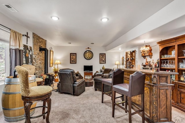 living area with visible vents, light colored carpet, recessed lighting, a wood stove, and a bar