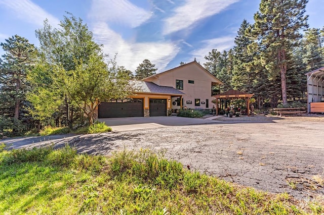 view of front of home featuring stone siding, a garage, driveway, and stucco siding