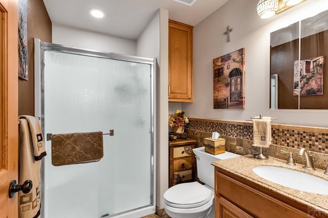 full bath with a wainscoted wall, toilet, a stall shower, tile walls, and vanity