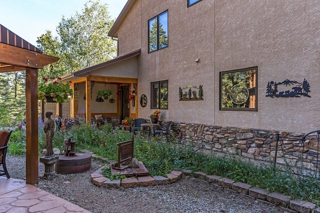 exterior space featuring stucco siding, stone siding, and a patio area