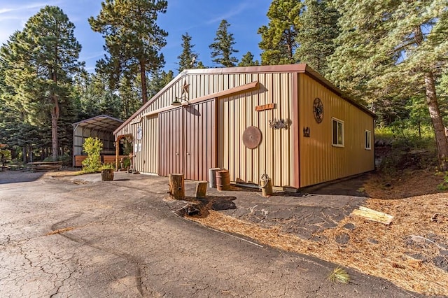 view of outbuilding featuring aphalt driveway, a carport, and an outdoor structure