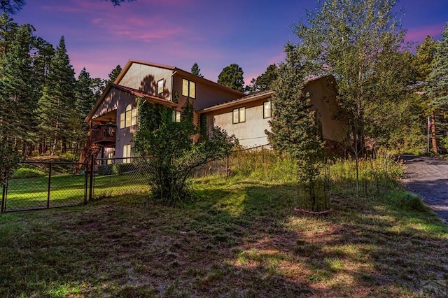 view of side of property featuring stucco siding, a lawn, and fence