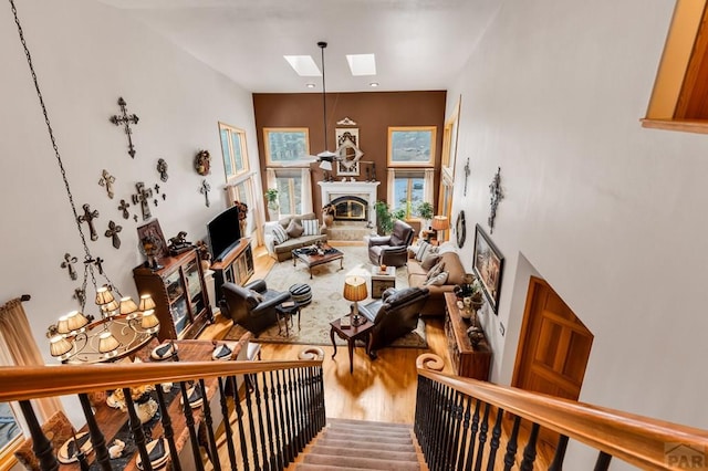 living area with a glass covered fireplace, a skylight, and wood finished floors