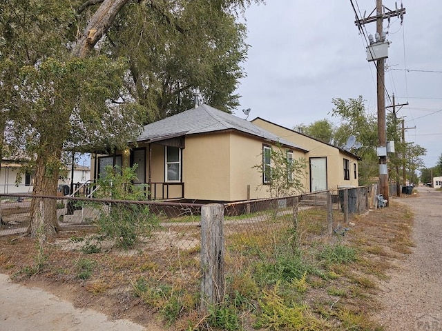 view of side of home with a fenced front yard and stucco siding