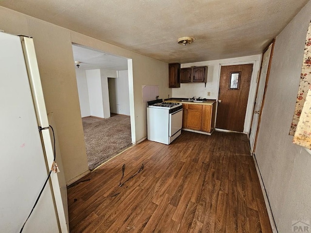 308 W Poplar St, Lamar, CO 81052 - kitchen featuring white appliances, dark wood-style flooring, light countertops, a textured ceiling, and a sink