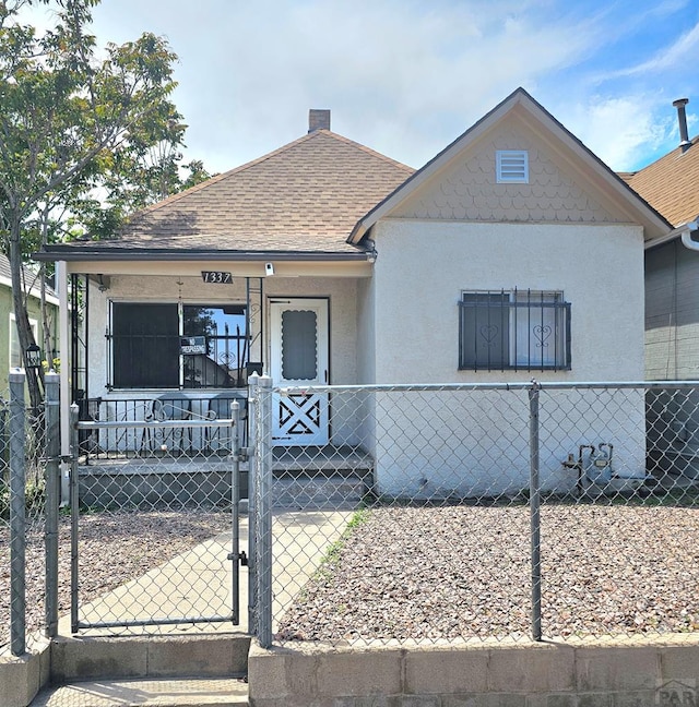 1337 Spruce St, Pueblo, CO 81004 - view of front facade featuring a gate, covered porch, a fenced front yard, roof with shingles, and stucco siding