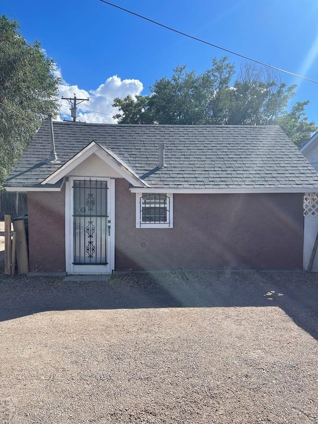 view of front of house featuring a shingled roof and stucco siding