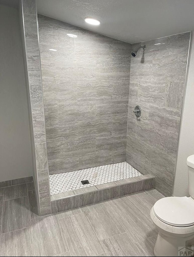 full bath featuring a textured ceiling, a stall shower, and toilet