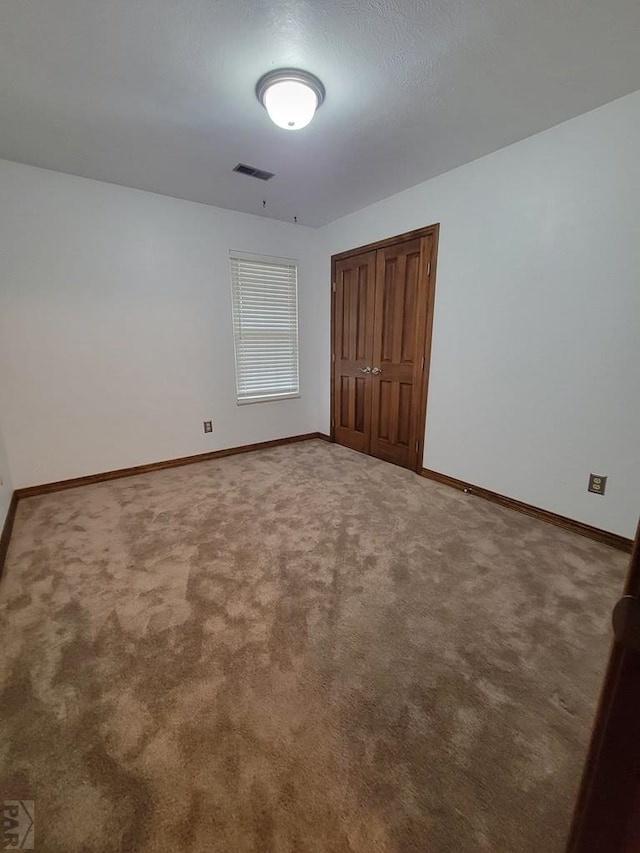 unfurnished bedroom featuring carpet, visible vents, and baseboards