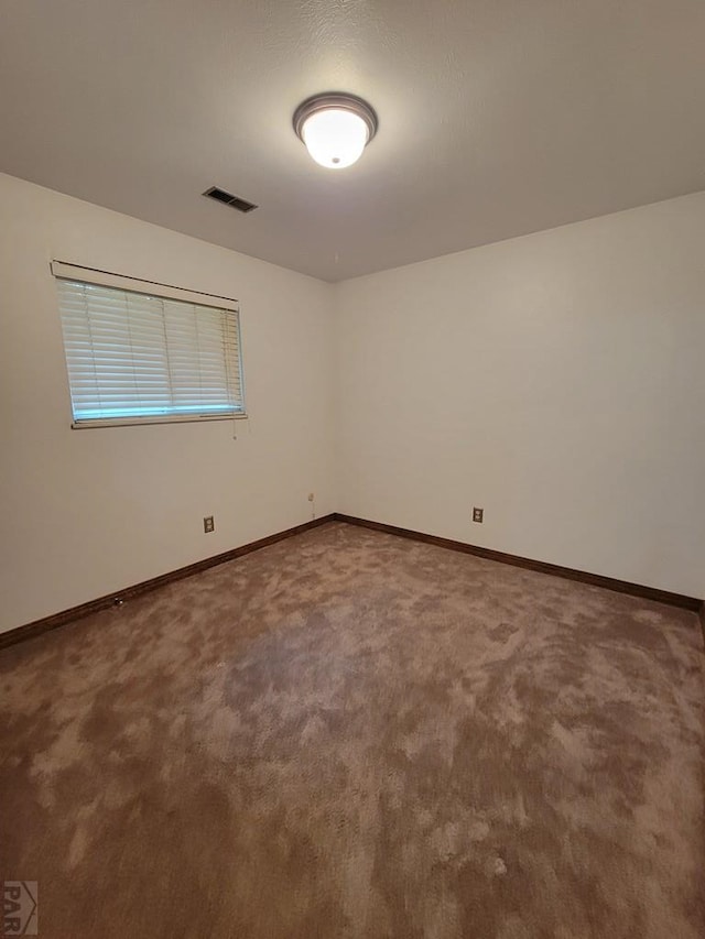 spare room featuring carpet floors, baseboards, and visible vents