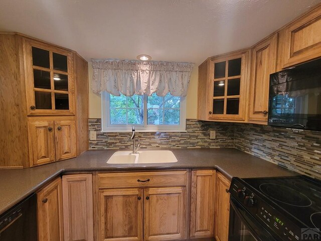 kitchen featuring black appliances, dark countertops, a sink, and glass insert cabinets